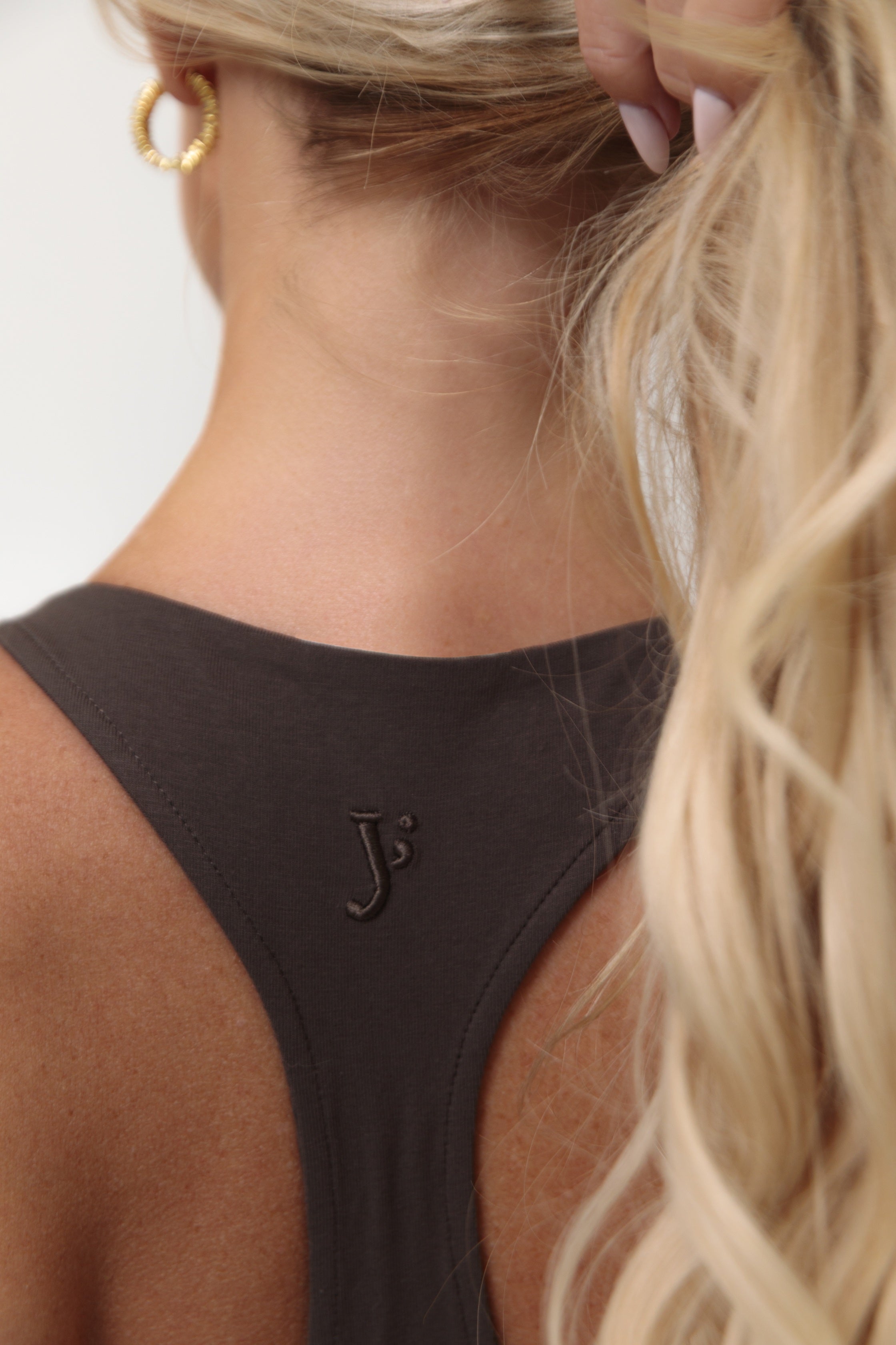 Chocolate Brown Racerback sports bra made from organic cotton with the y brand logo embroidered mid back on a person wearing it.