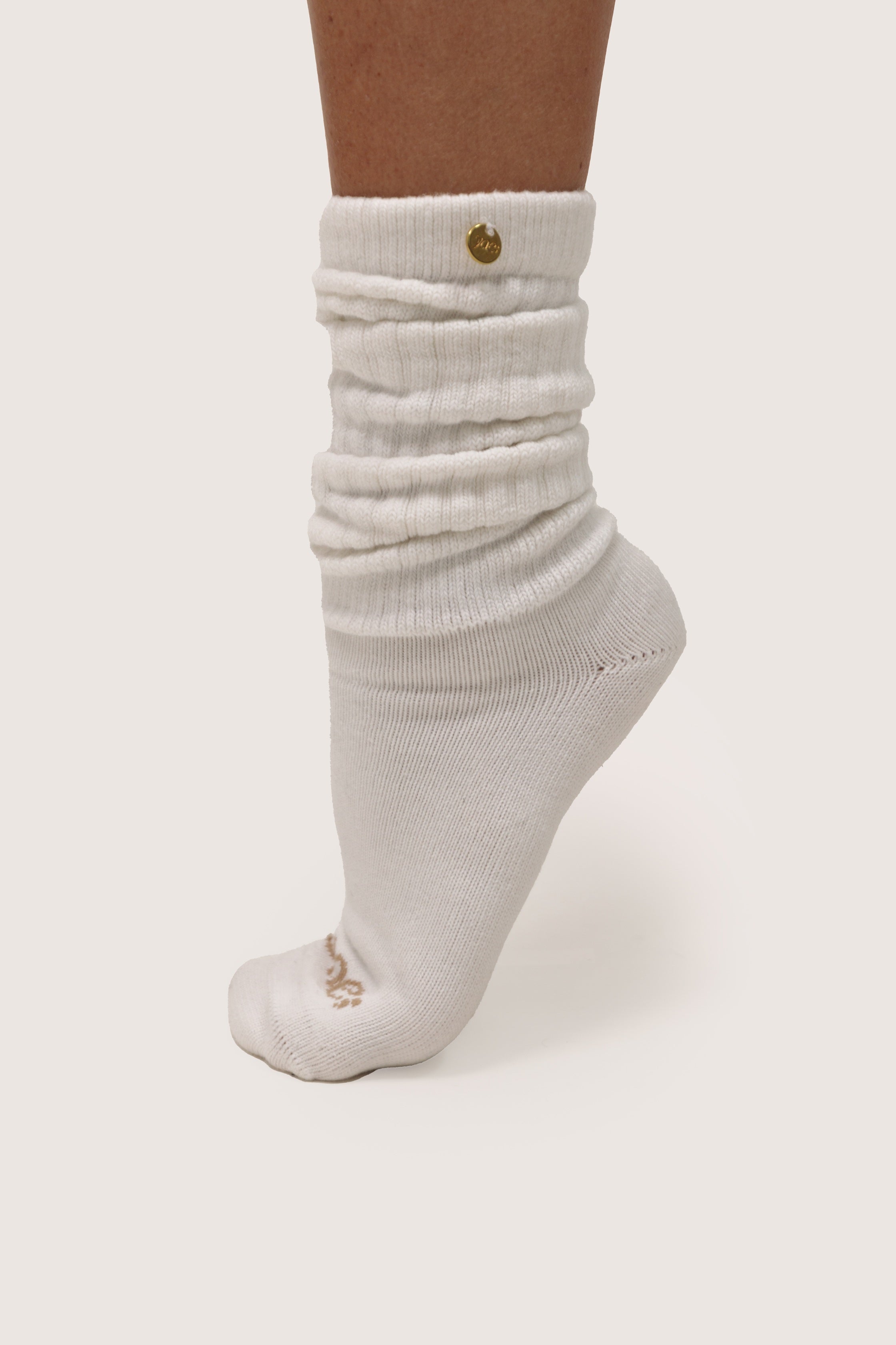 White ribbed socks with a gold button on a white background