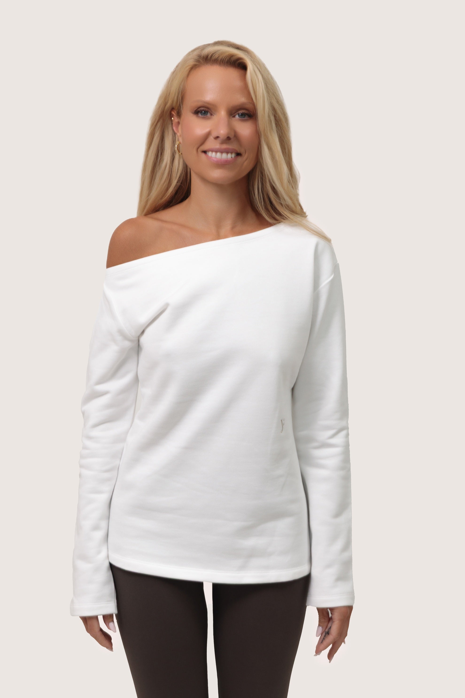 Woman wearing a white off-shoulder sweater on a plain background