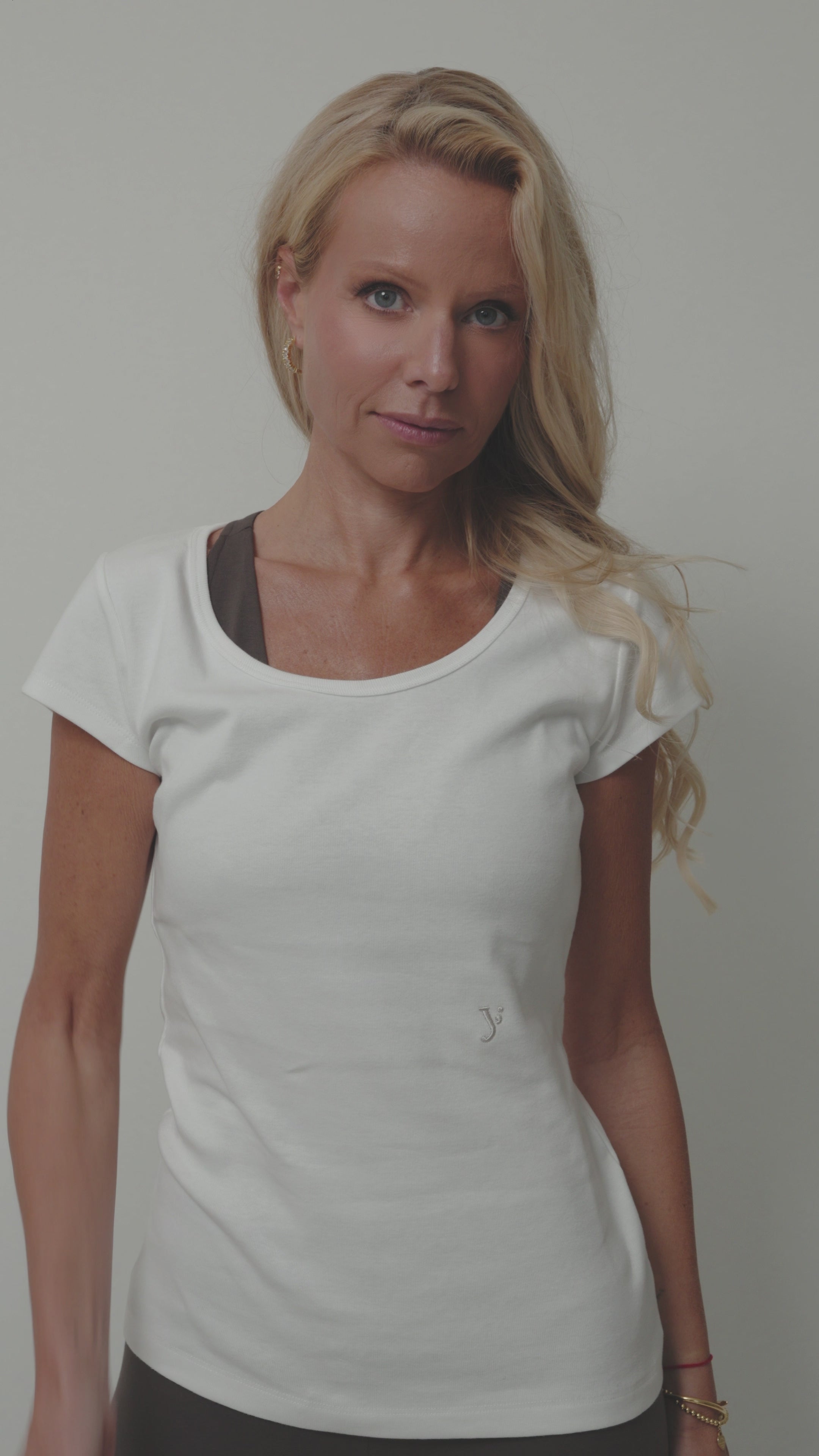 woman showcasing a white organic cotton t-shirt with capped sleeves, a y embroidery and a scooped neckline